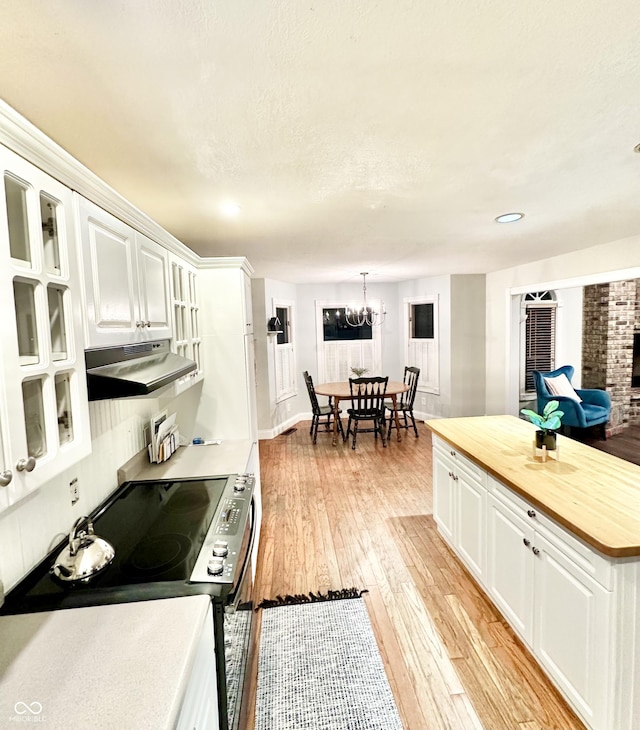 kitchen featuring butcher block counters, stainless steel electric range oven, a textured ceiling, light hardwood / wood-style flooring, and white cabinets