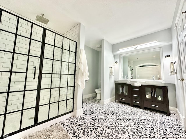 bathroom featuring tile patterned flooring, vanity, toilet, and tiled shower