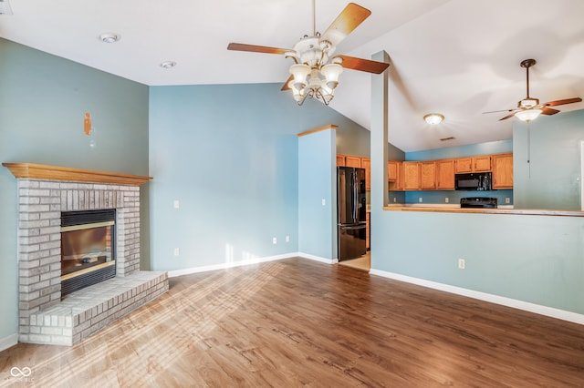 unfurnished living room featuring light wood-type flooring, lofted ceiling, ceiling fan, and a fireplace