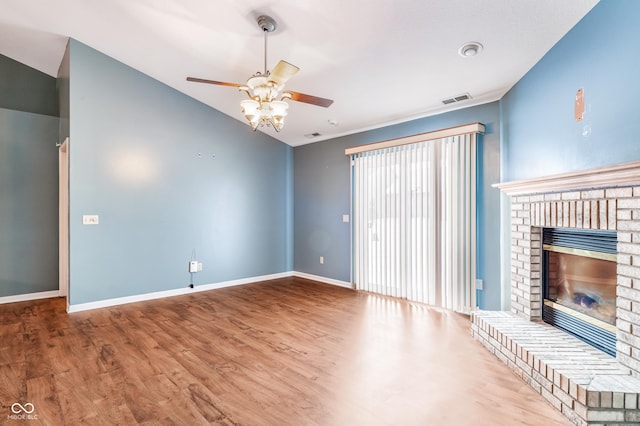 unfurnished living room featuring lofted ceiling, a brick fireplace, hardwood / wood-style floors, and ceiling fan