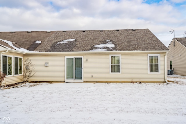 snow covered rear of property featuring central AC unit