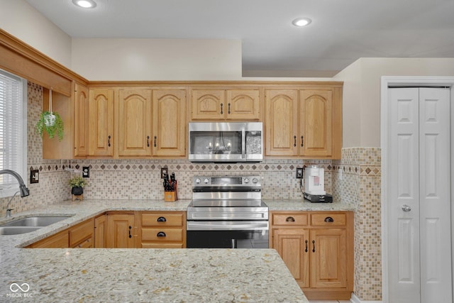 kitchen with sink, appliances with stainless steel finishes, backsplash, light stone counters, and light brown cabinetry