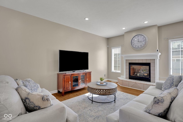 living room featuring plenty of natural light, a tiled fireplace, and light hardwood / wood-style floors