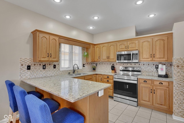 kitchen featuring light stone counters, sink, stainless steel appliances, and kitchen peninsula