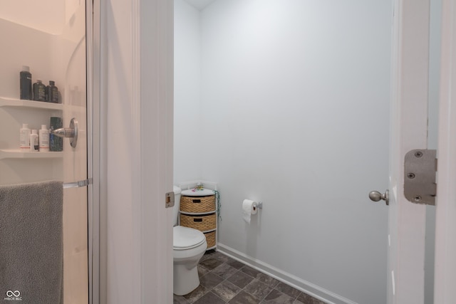 bathroom featuring a shower with shower door and toilet