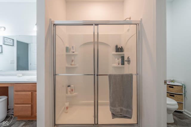 bathroom with vanity, a shower with shower door, and toilet