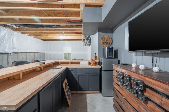 bar featuring stainless steel refrigerator and wood counters