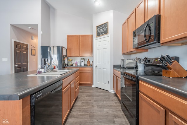 kitchen featuring hardwood / wood-style flooring, a center island, sink, and black appliances