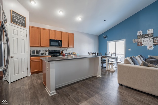 kitchen with vaulted ceiling, pendant lighting, dark hardwood / wood-style flooring, a kitchen island with sink, and black appliances