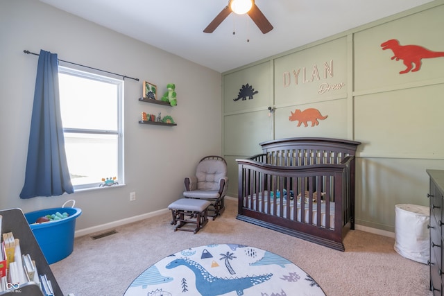 bedroom featuring ceiling fan, light colored carpet, and a crib