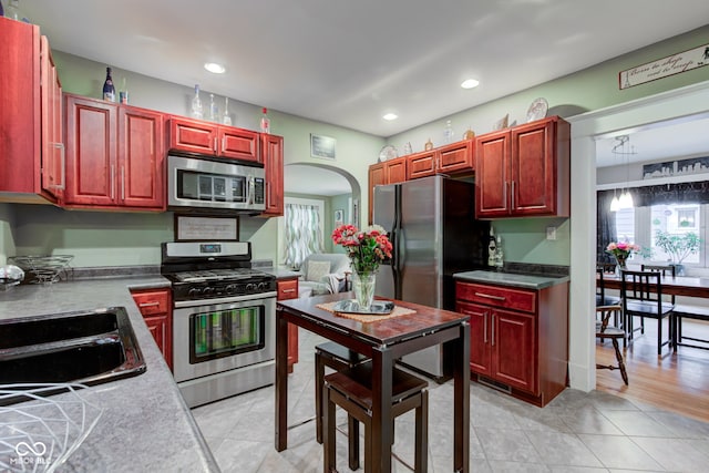 kitchen with stainless steel appliances, sink, pendant lighting, and light tile patterned floors