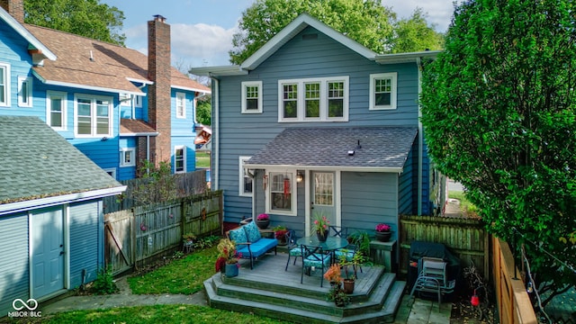 rear view of house featuring a wooden deck and a storage unit