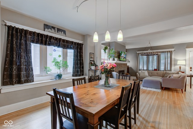 dining area featuring a tile fireplace and light wood-type flooring