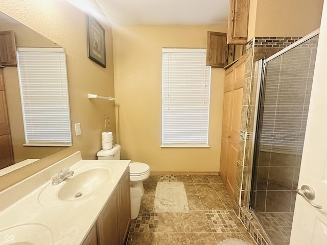 bathroom featuring vanity, a shower with shower door, and toilet