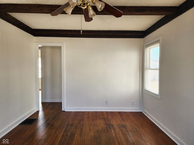 empty room with beam ceiling, visible vents, baseboards, and dark wood-style floors