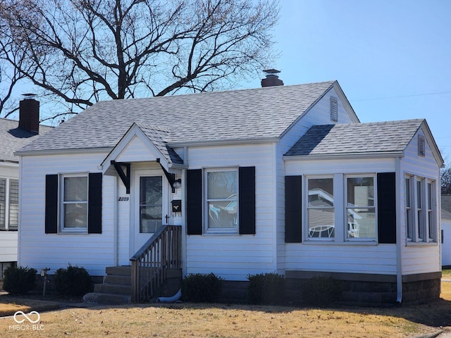 bungalow with a shingled roof and a chimney