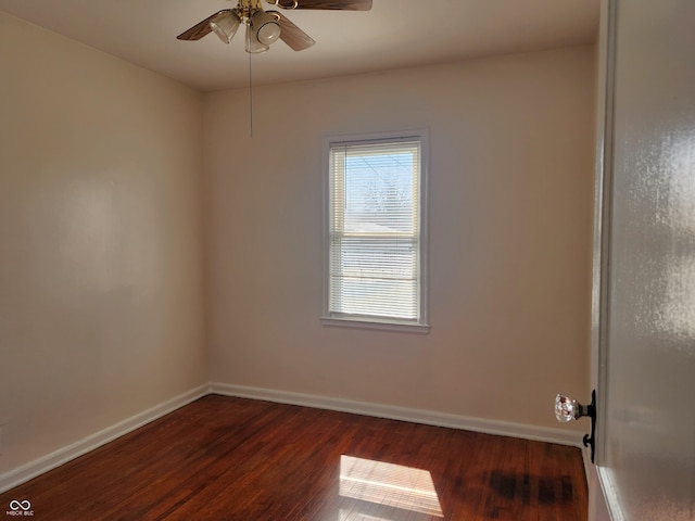 spare room with baseboards, ceiling fan, and dark wood-style flooring