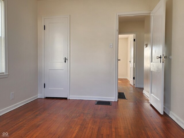 unfurnished bedroom featuring visible vents, baseboards, and dark wood-style floors