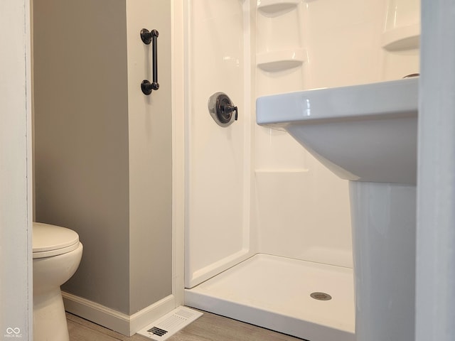 full bathroom featuring a stall shower, toilet, and baseboards