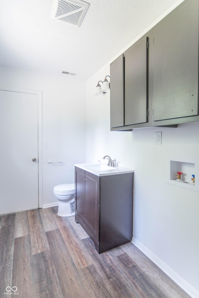 bathroom with visible vents, baseboards, toilet, wood finished floors, and vanity