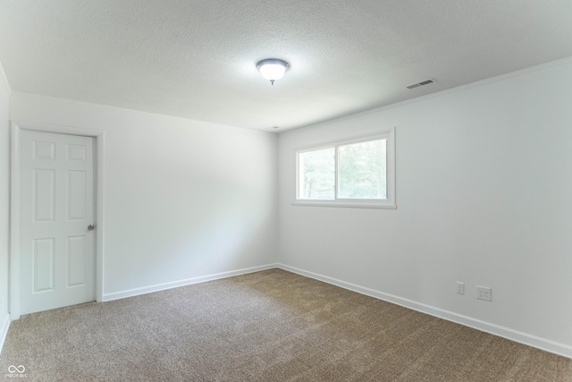 carpeted spare room with baseboards, visible vents, and a textured ceiling