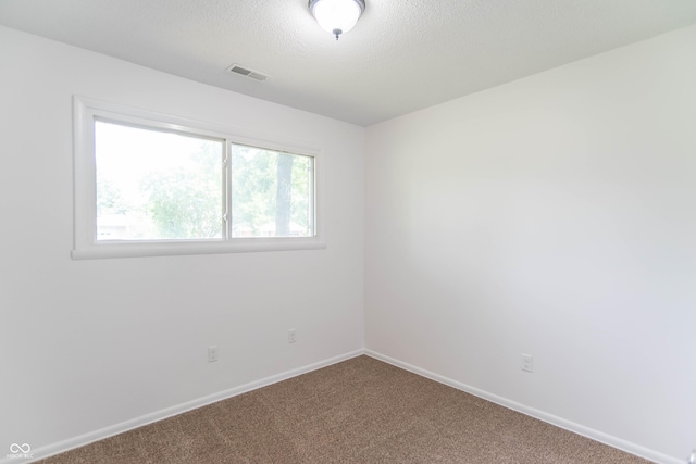 carpeted spare room with visible vents, baseboards, and a textured ceiling