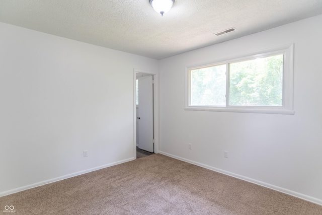 carpeted empty room featuring visible vents, a textured ceiling, and baseboards