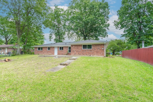 back of house with a yard, fence, and brick siding