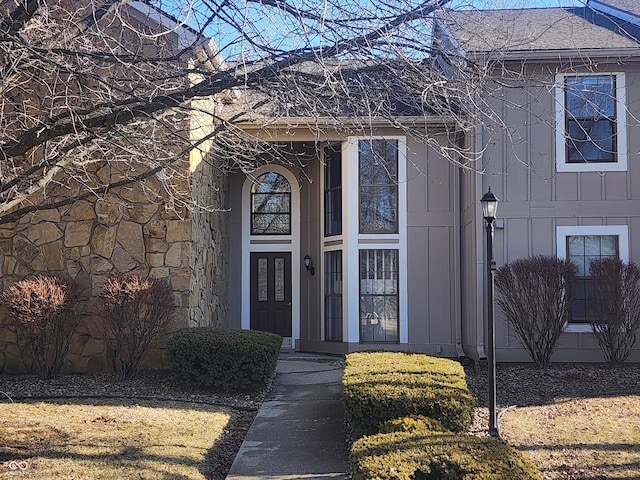 view of exterior entry with board and batten siding and roof with shingles