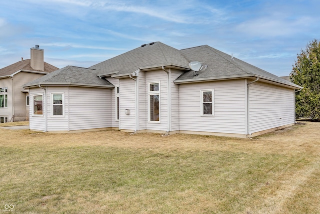 rear view of property with roof with shingles and a yard