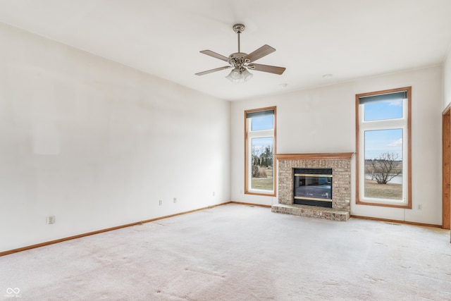 unfurnished living room featuring a ceiling fan, carpet flooring, a fireplace, and baseboards