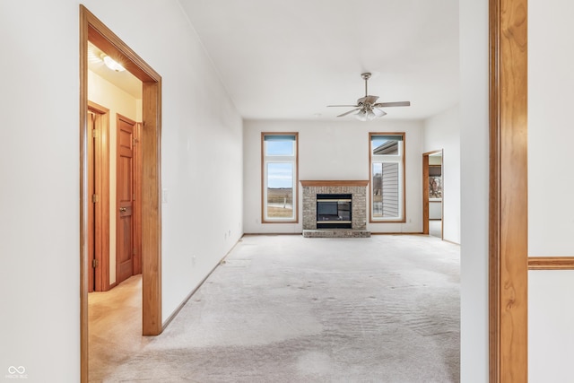 unfurnished living room featuring ceiling fan, carpet floors, a brick fireplace, and baseboards