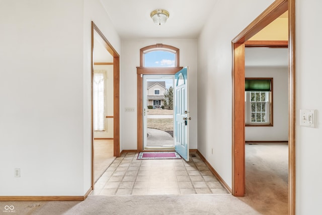 entryway featuring baseboards and light colored carpet