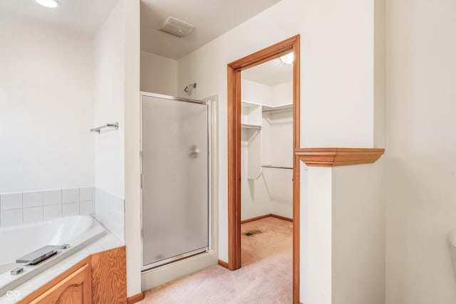 bathroom with a stall shower, a walk in closet, a garden tub, and visible vents