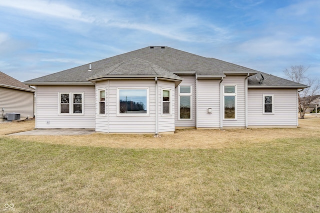 back of property with a shingled roof, cooling unit, a patio area, and a yard