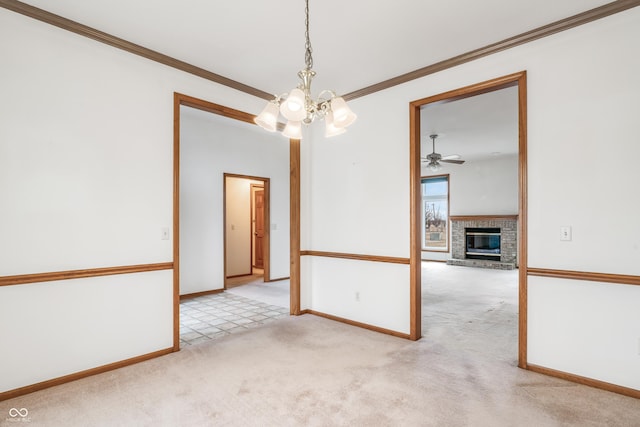 spare room with a notable chandelier, carpet floors, baseboards, a brick fireplace, and crown molding