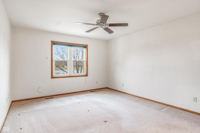 spare room featuring light carpet, visible vents, and baseboards