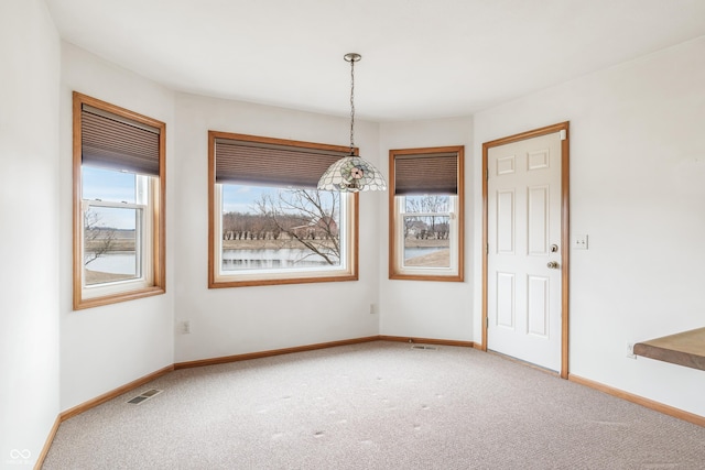 unfurnished dining area featuring a wealth of natural light, carpet flooring, and baseboards