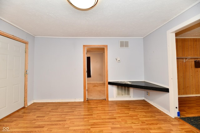 interior space featuring built in desk, a textured ceiling, and light hardwood / wood-style floors