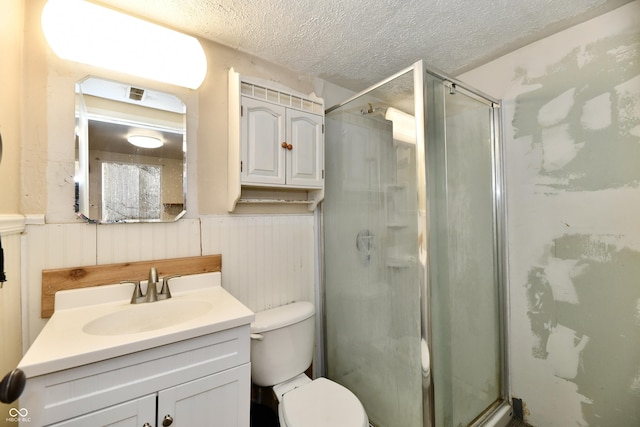 bathroom with vanity, a shower with shower door, toilet, and a textured ceiling