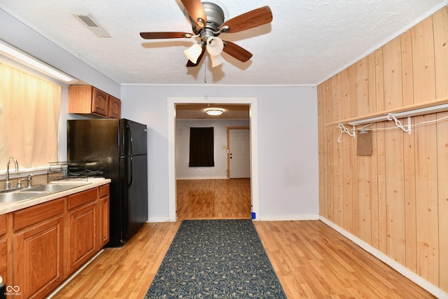 kitchen featuring black refrigerator, sink, a textured ceiling, and light wood-type flooring