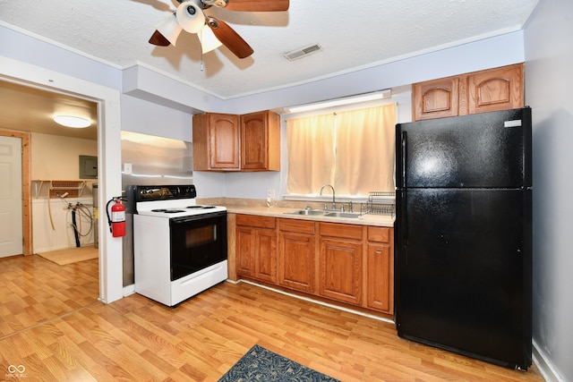 kitchen featuring sink, light hardwood / wood-style flooring, range with electric stovetop, a textured ceiling, and black fridge