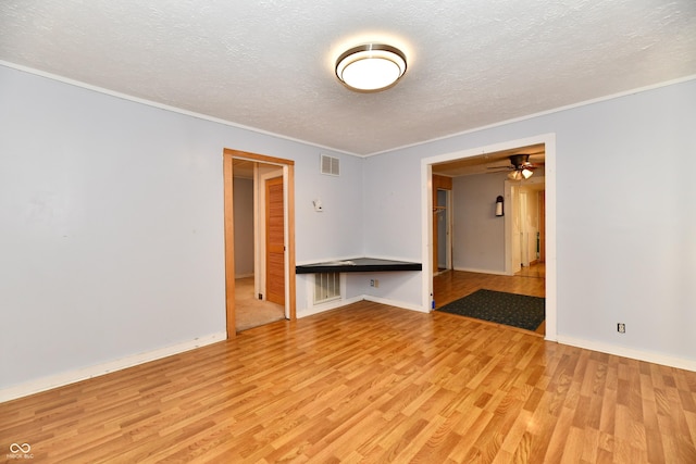 unfurnished room featuring crown molding, light hardwood / wood-style flooring, and a textured ceiling