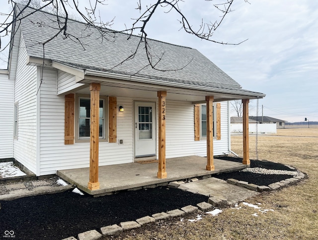 exterior space with covered porch and a shingled roof