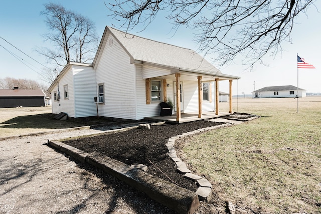 view of side of home featuring covered porch, cooling unit, and a yard