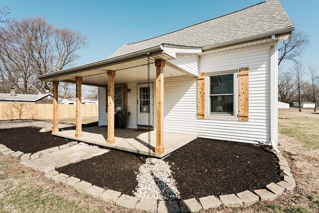 back of house featuring roof with shingles and fence