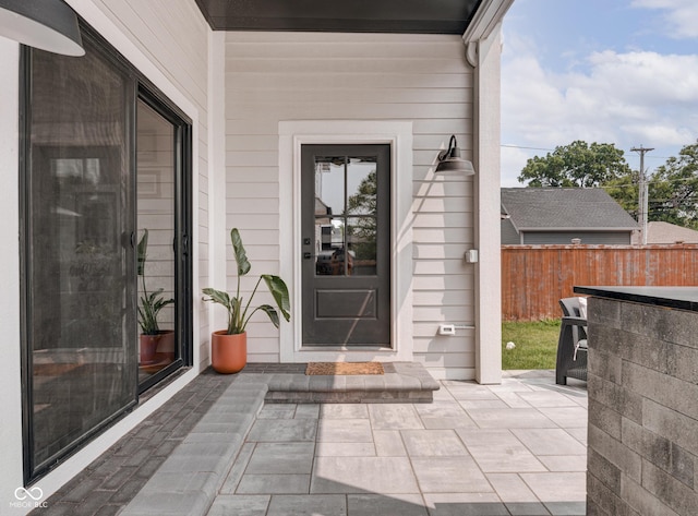 view of exterior entry with a patio, exterior bar, and fence