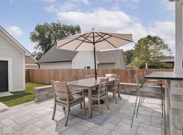 view of patio featuring outdoor dining space, a fenced backyard, and an outdoor bar