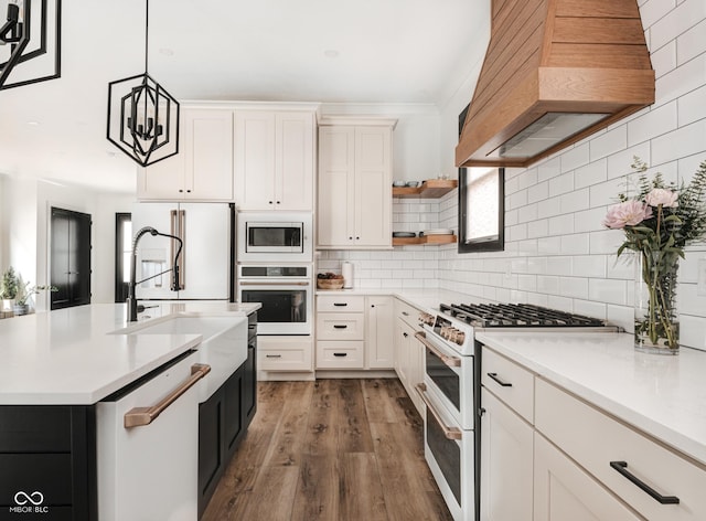 kitchen featuring pendant lighting, white appliances, custom range hood, and white cabinets