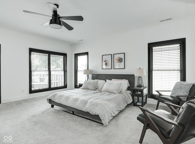 bedroom with light carpet, ceiling fan, visible vents, and multiple windows